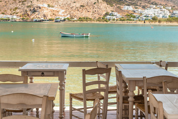 Tables with chairs on coastal promenade overlooking the sea. Sifnos island, Greece