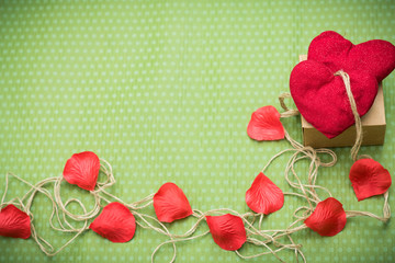 Valentine day. A red heart tied with an old thread to a gift box lies on a green polka dot background. Valentine's Day. Heart pendant. Space for text. Red heart. Eighth of March.