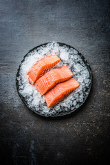 Portioned raw salmon fillets in ice on plate - Top of view
