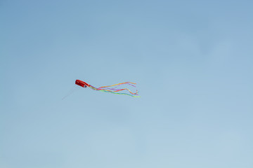 Red kite flying high against blue sky