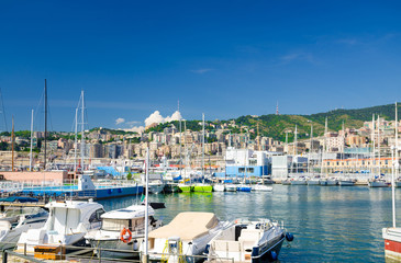 Fototapeta na wymiar Port Porto Antico harbor with luxury white yachts in historical centre of old european city Genoa Genova with blue sky in clear summer day and green hill with buildings background, Liguria, Italy
