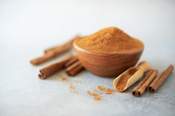 Cinnamon sticks and powder on grey background. Spices for ayurvedic treatment. Alternative medicine concept