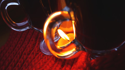 Mulled wine in glass mugs, burning candle on a dark red background. Red Hot wine