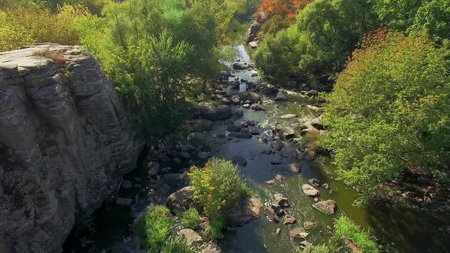 4K aerial view of autumn canyon, mountain river in canyon, flying over buky canyon in the autumn, big stones in the autumn river, waterfall in autumn colors with big stones