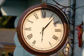 Fototapeta na wymiar Garden clock hanging on wooden outside wall of summer house.