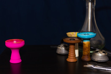 Hookah and four different hookah bowls and kalaud on the table close-up on a dark blue background