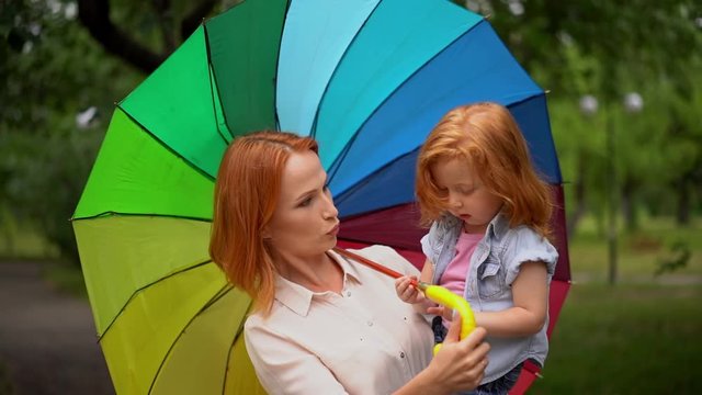 Happy mom and daughter under colored umbrella