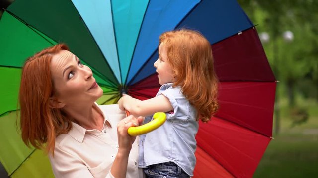 Happy mom and daughter under colored umbrella