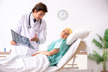 Young handsome doctor visiting female oncology patient 