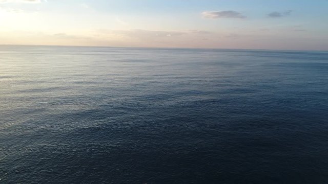 A footage of a sunset from above the sea via drone, clear water and colourfull clouds, 4k resoluted shooting