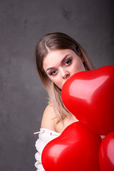 Young beautiful girl with red balloons in heart shape