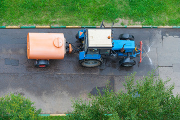 Top view on a tractor with tank for washing the asphalt road in the park
