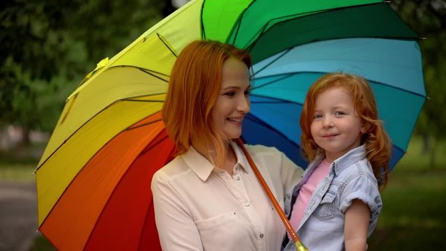 Happy mother and child under rainbow umbrella