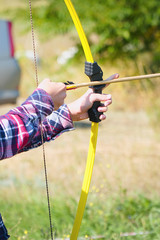 Hand holds archery and arrow. Bow shooting