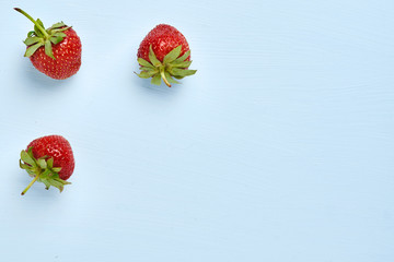 Food concept with sweet delicious strawberries on blue background, healthy organic food image, minimalistic fruit concept. top view.