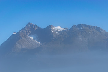 Fototapeta na wymiar Misty obscured view of snow covered mountain in Glacier Bay, Alaska