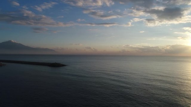 A footage of a sunset from above the sea via drone, clear water and colourfull clouds, 4k resoluted shooting