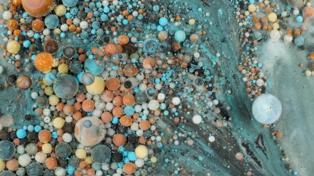 Colorful paint in bubbles organically moves in the liquid