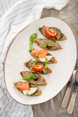 Brushetta set for wine. Variety of small sandwiches on white plate on the table