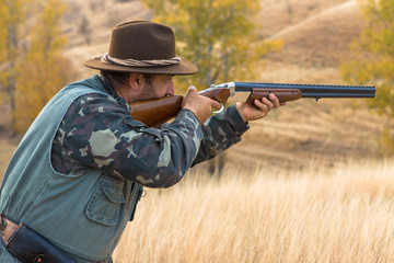 Hunter with a hat and a gun in search of prey in the steppe	