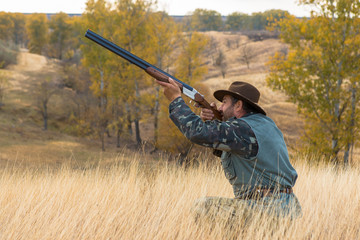 Hunter with a hat and a gun in search of prey in the steppe	