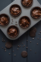 Hygge homemade sweeets. Batter for chocolate muffins and chocolate drips in baking tray on dark background top view