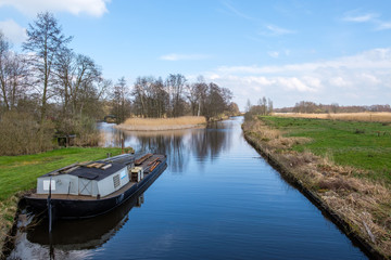 Obraz premium Early spring view on Giethoorn, Netherlands, a traditional Dutch village with canals. A typical low boat along the lawn in a ditch.