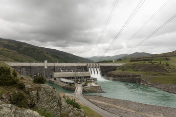 The Clyde hydroelectric power dam spilling large amounts of excess water. Electricity lines leading to the power station. Clyde, Otago, New Zealand.