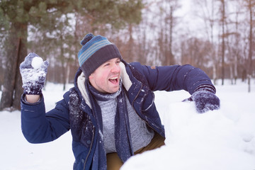 European mature man in warm clothes playing with snow outdoor