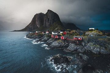 Fototapeta na wymiar Panorama of famous tourist attraction Hamnoy fishing village on Lofoten Islands near Reine, Norway with red rorbu houses in autumn with clouds and blue sky and ocean waves.