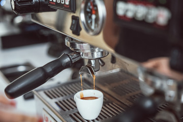 Professional espresso machine pouring fresh coffee into white ceramic cup