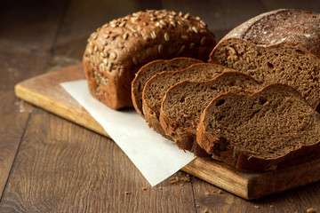 Creative background, freshly baked sliced rye bread on a wooden cutting board, flat lay, copy space. The concept of fresh pastry, black bread.