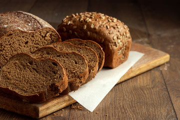 Creative background, freshly baked sliced rye bread on a wooden cutting board, flat lay, copy space. The concept of fresh pastry, black bread.
