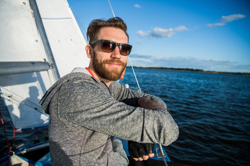 Nice happy bearded man sailor thumbing up and evincing positivity while at his yacht or boat on a...
