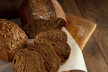 Creative background, freshly baked sliced rye bread on a wooden cutting board, flat lay, copy space. The concept of fresh pastry, black bread.