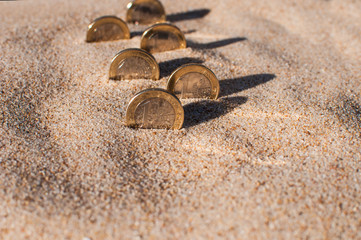 Fototapeta na wymiar six of one Euro coins stand on edge in the sand