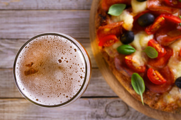 Beer and pizza on wooden plate. Ale and  snack. Overhead, horizontal
