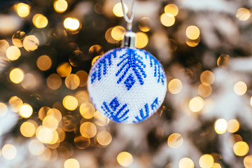 Blue white christmas ball on fir tree branch close up golden yellow light bokeh background