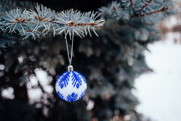 Blue white christmas ball on fir tree branch close up