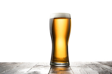 Frosty glass of light beer on wood table