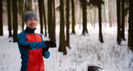 Runner wearing warm sporty clothes looks at a modern smart clock and counts up spent calories