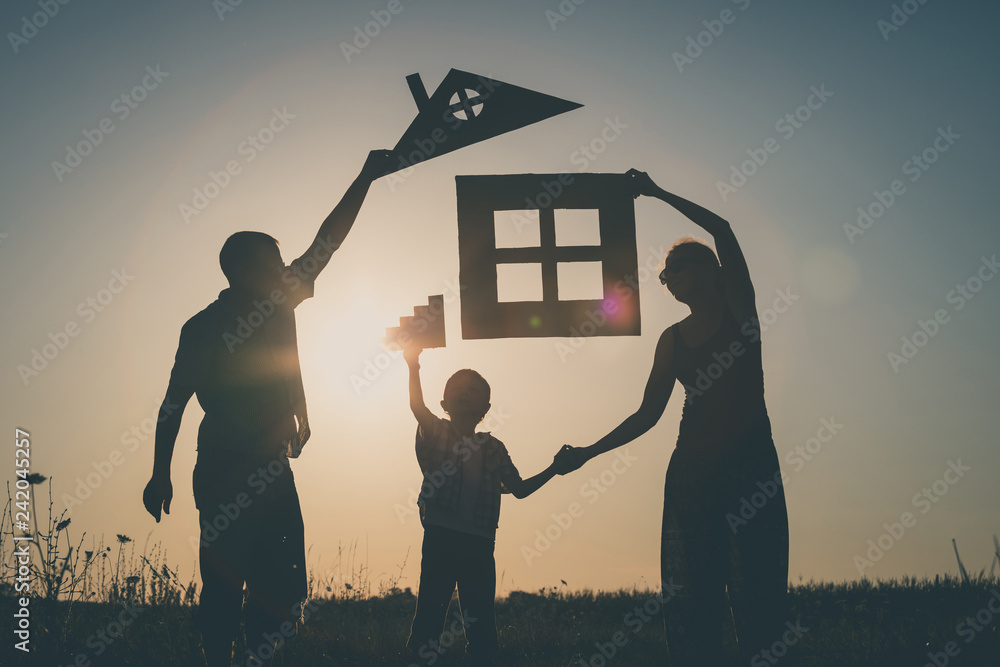 Wall mural Happy family standing on the field at the sunset time.