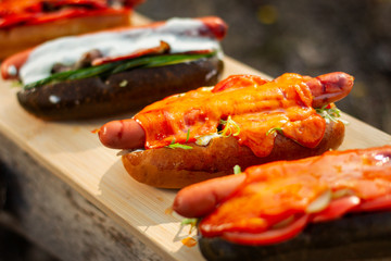 Hotdog with salad, cheese and red pepper, on wooden board.