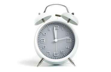 Table alarm clock shows time 1 minute to 12 o'clock with gray clock face, 11.59 AM PM, on white background