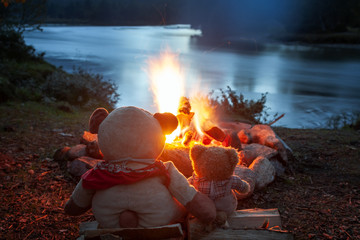 Zwei Teddybären sitzen verträumt am Lagerfeuer