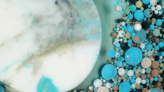 Colorful paint in bubbles organically moves in the liquid