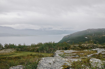 Scenic view in Northern Norway. Fjord and snow mountains in the fog