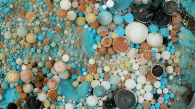 Colorful paint in bubbles organically moves in the liquid
