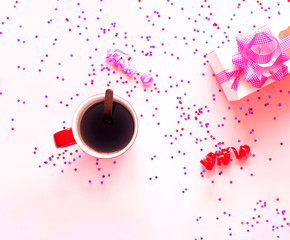 Cup of coffee and Gift box with pink bow on pink pastel background with sparkles. Festive concept.  