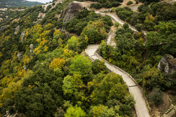 aerial nature landscape photography of paved curved narrow pilgrim road path way in highland mountain woodland nature scenic environment from above